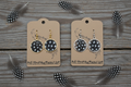 Rustic flat lay of Spotted Beauty guinea fowl feather open bezel earrings in gold and silver on weathered barn wood